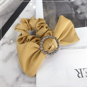 Detail of yellow satin scrunchie with a sparkling rhinestone buckle and large bow