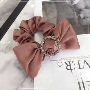 Close-up of silk satin scrunchie with rhinestones buckle and large bow detail