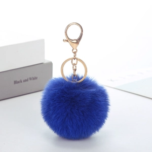 Detail of soft bright blue faux rabbit fur pompom keychain with golden metal clasp