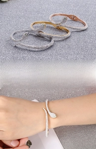 Detailed view of three-color snake bracelets with green gem eyes and sparkling crystals