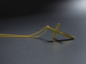 Detailaufnahme eines minimalistischen goldenen Edelstahl-Kreuzanhängers mit einer O-Kette