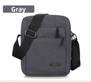 Close-up of grey oxford fabric messenger bag with metal logo and front zipper pocket