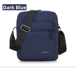 Detail view of dark blue Oxford fabric shoulder bag featuring a metal brand logo plate