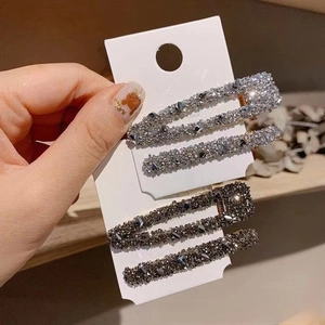 Détail de deux ensembles de barrettes de luxe en strass en finitions argent et noir anthracite