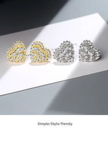 Close-up of gold and silver heart stud earrings with sparkling pavé cubic zirconia