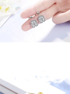 Close-up of square cluster zircon earrings with silver finish held by hand