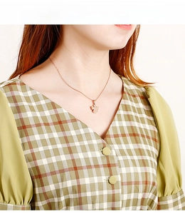 Dettaglio della collana con ciondolo a fiore oro rosa indossata da una modella elegante