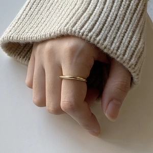 Polished minimalist gold band ring worn on hand with cozy winter sweater texture