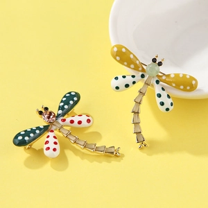 Macro detail of colorful enamel dragonfly brooches with polka dots and crystal accents