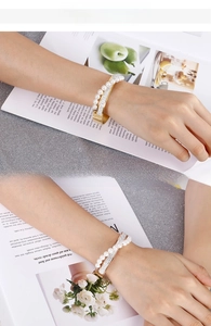 Detailed view of women's gold layered bangle with pearls and sparkling rhinestones on wrist