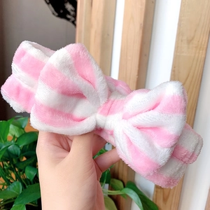Detailed view of pink and white striped plush headband featuring a large bow knot accessory