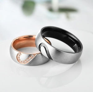 Close-up of titanium steel couple rings with heart pattern and inlaid small diamonds