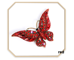 Detailed close-up of red crystals and antique gold finish on the butterfly brooch