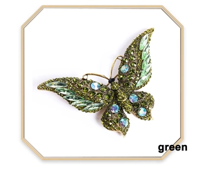 Detailed view of vintage gold butterfly brooch with green and iridescent crystals