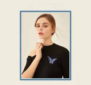 Close-up of a blue crystal butterfly brooch pinned on a black knit shoulder top