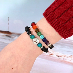 Detail of chakra beads bracelet and matte black beads with silver tree of life charm