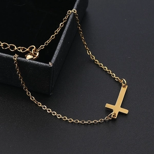 Vue détaillée d'un pendentif croix inversée plaqué or poli sur une fine chaîne dorée
