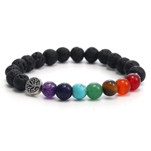 Detail of lava rock chakra bracelet featuring a silver Tree of Life charm on white background