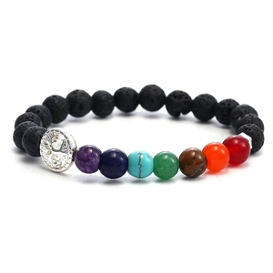 Macro shot of 8-10mm black volcanic stone beads with a silver tree of life charm and chakra gems