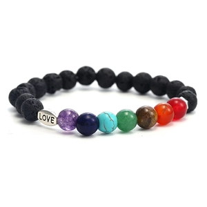 Macro detail of natural volcanic stone beads and silver LOVE charm on colorful bracelet