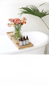 Detail of expandable bamboo bathtub tray with multi-functional storage over a white tub