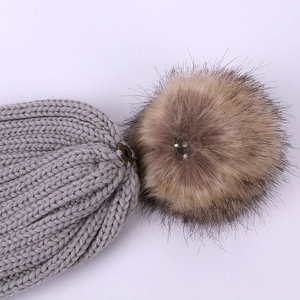 Bonnet en tricot gris avec pompon marron détachable et détail de bouton pression