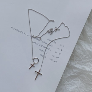 Close-up of a 925 silver necklace with minimalist double cross pendants on an open book