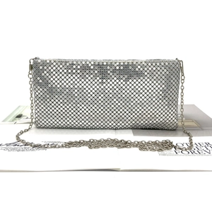 Detailed shot of silver sequin metal mesh clutch bag with thin chain strap on a magazine