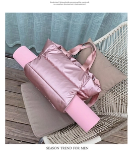 Pink quilted fitness bag with specialized side strap holding a yoga mat on a chair