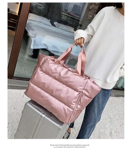 Pink quilted fitness travel bag with luggage sleeve shown on a silver suitcase handle