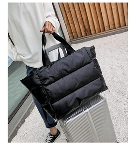 Black quilted fitness bag with luggage strap sleeve shown on a silver suitcase handle