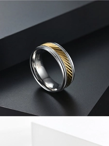 Detail showing brushed stainless steel band with gold knurled pattern and inner engraving