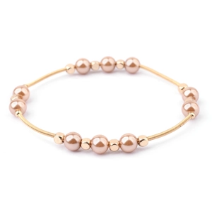 Macro detail of elastic champagne gold wire bracelet with metallic pearls and beads