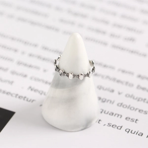Dettaglio di un anello geometrico in argento sterling S925 su un supporto conico bianco
