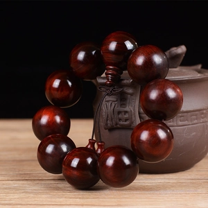 Macro detail of 25mm Red Sandalwood beads with natural wood grain texture and tassel