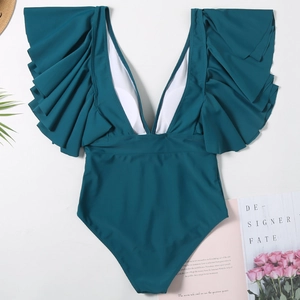 Detail of dark green V-neck swimsuit with ruffled shoulders and beach accessories
