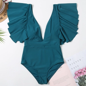 Flat lay of teal deep V-neck swimsuit with ruffled sleeves and vacation accessories