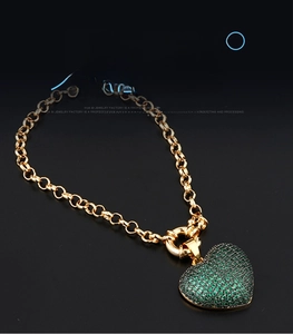 Nahaufnahme der goldenen Gliederkette mit herzförmigem Micro-Pave Anhänger in Grün