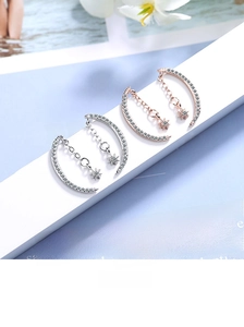 Detail of moon and star drop earrings with sparkling rhinestones in silver and rose gold
