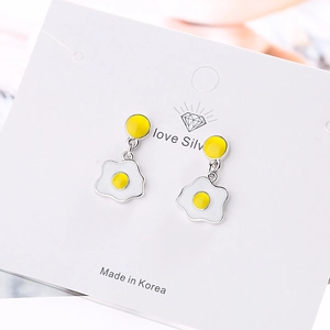 Creative fried egg studs with white base and yellow yolk on a white jewelry card