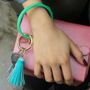 Detail of green silicone geometric keychain with leather tassel and gold metal ring hook