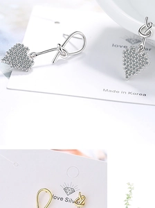 Detail view of asymmetric heart-shaped earrings with rhinestones and knot design