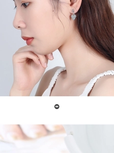 Close-up of asymmetrical heart earrings with shimmering rhinestones on a female model