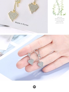 Close-up of asymmetric heart stud earrings with crystals in gold and silver finish