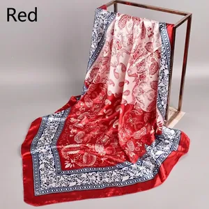 Detail view of red paisley print square silk scarf hanging to show texture and gloss