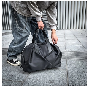 Outdoor street style view of a large black travel duffel bag held by a person
