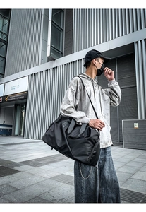 Outdoor view of a black high-capacity waterproof travel bag featuring dual carry handles