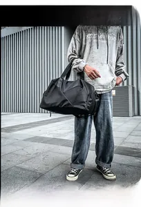 Detail of a black nylon travel bag featuring reinforced handles and sleek geometric design