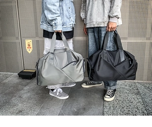 Gray and black sports travel bags for men and women shown in a street lifestyle setting