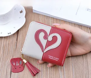 Macro view of bicolored leather wallet with heart stitching and rabbit tassel detail